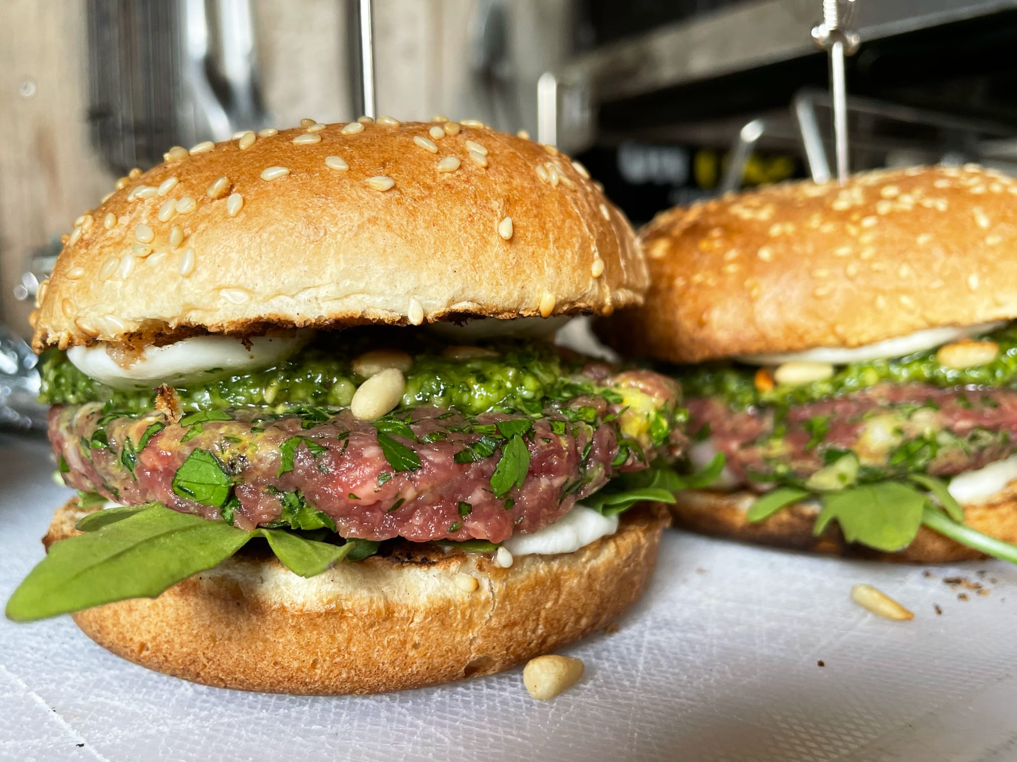 Twee raw burgers - belegd met rucola, mozzarella, tartaar, pesto en pijnboompitten